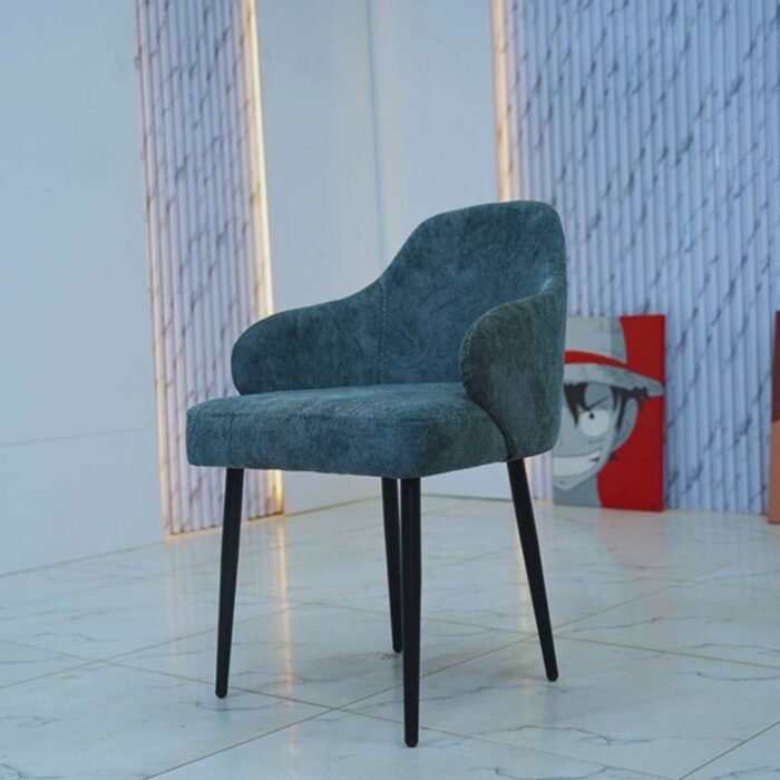 Chaise moderne en velours bleu pétrole avec dossier enveloppant et pieds fins noirs.