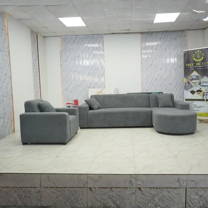 Canapé d'angle gris anthracite avec méridienne arrondie et fauteuil assorti dans un showroom.